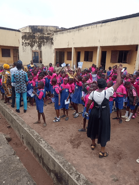 Pupils gathered with a teacher, holding up the materials they have received.