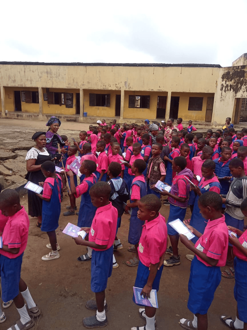 Pupils in uniform standing in lines, each reading the exercise book they have just been given.
