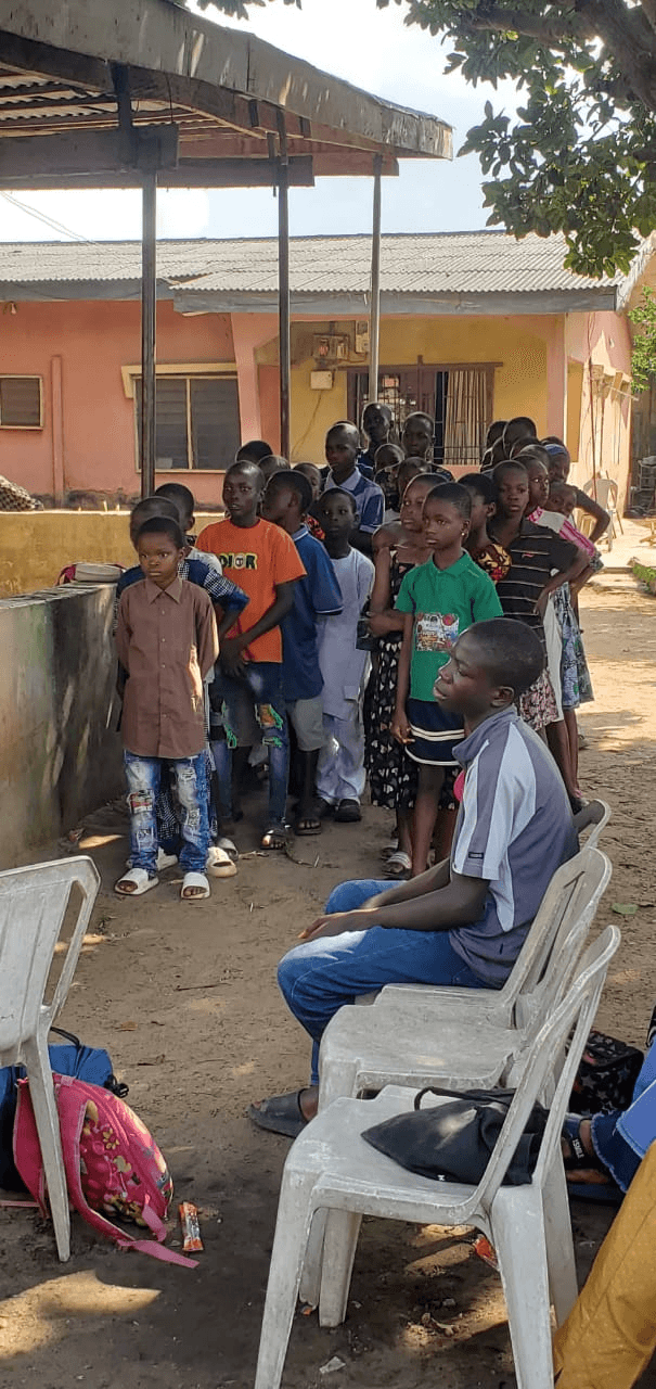 Children standing in a queue in a courtyard, waiting their turn.
